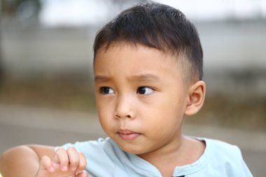 Düşünceli bir ifadeye sahip genç bir çocuk düşünceli bir şekilde uzaklığa bakar. Onun masum cazibesi bir anlık merak ve sükuneti yakalar..