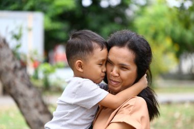 Bir anne ve çocuğu arasındaki iç açıcı bir an, açık hava ortamında sevgi ve şefkat göstererek, bağlarının güzelliğini yakalıyor..