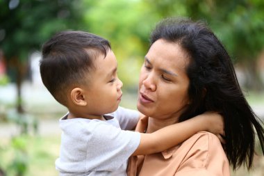 Bir anne ve küçük oğlu arasında samimi bir an. Sahne, onların sevgi dolu bağlarını ve neşeli ilişkilerini doğal bir ortamda yakalar..