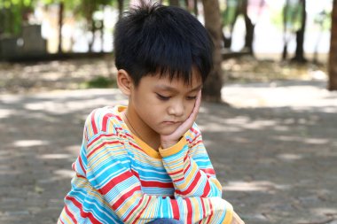 Genç bir çocuk parkta tek başına oturuyor, düşüncelere dalmış, dalgın bir ifadeyle. Bu sahne, doğada derin düşüncelere ve yalnızlığa ait hisleri yakalar..