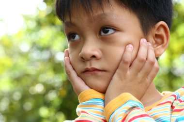 Düşünceli bir çocuğun yakın plan portresi, sakin bir açık hava ortamında, doğada bir dizi duygu ve masumiyet sergiliyor..