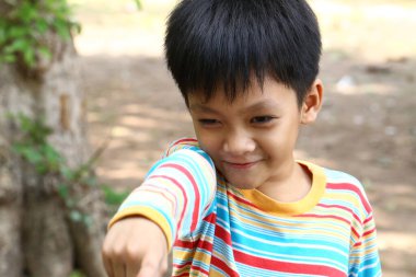 Neşeli genç bir çocuk neşeli bir şekilde açık havayı gösteriyor, parlak bir gülümseme ve neşe hissi sergiliyor. Çocukluk ve mutluluk temaları için mükemmel..