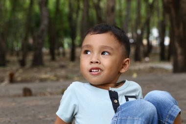 Ağaçlar ve doğa ile çevrili sakin bir orman ortamında eğlenen neşeli bir çocuk. O an, masumiyet ve neşe hissini yakalar..