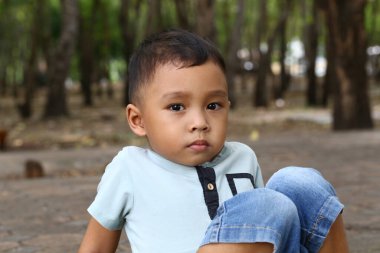 Düşünceli genç bir çocuk sakince ağaçlarla çevrili açık havada oturur. İfadesi bir anlık düşüncelere ve masumiyete sahne oluyor. Çocukluk, doğa ve sükunet temaları için mükemmel..
