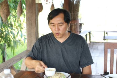 Açık hava ortamında lezzetli bir yemeğin tadını çıkaran bir adam. Kırsal çevre ve yemyeşil yeşil huzurlu bir yemek deneyimi yaratıyor..