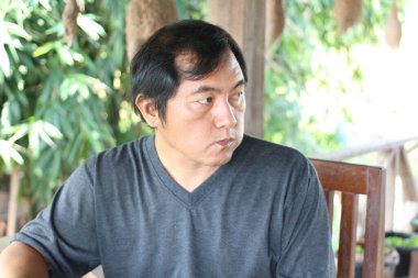 Doğal yeşil bir çevrede oturan düşünceli bir adam. Bu resim, sakin bir duygusal ifadeyi vurgulayarak, derin düşüncenin ve huzurun özünü yakalar..