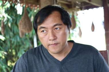 Dalgın bir adam, yemyeşil yeşilliklerle çevrili sakin bir ortamda yakalanır. Onun düşünceli ifadesi bir sakinlik ve içgözlem duygusunu uyandırıyor..