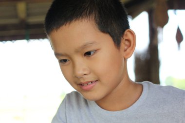 Neşeli bir gülümsemeyle açık havada eğlenen genç bir çocuk. Bu samimi portre çocukluk masumiyetinin ve merakının özünü doğal bir ortamda yakalıyor..