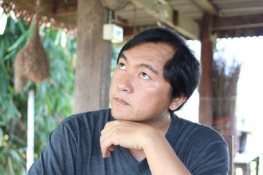 Dalgın bir adam, sakin bir açık havada yukarı bakar. Görüntü, doğanın güzelliği arasında bir yansıma ve sükunet anı yakalar..