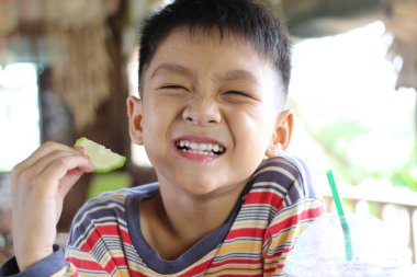 Neşeli bir çocuk, neşeli bir gülümsemeyle açık havada sağlıklı bir şeyler atıştırır. Mutluluğun ve çocukluktaki kaygısız anların özünü yakalar..