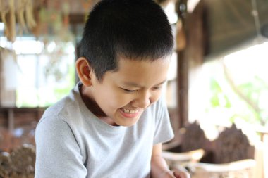 Neşeli bir çocuk kapalı bir ortamda parlak bir şekilde gülümser, çocukluk neşesi ve sıcaklığının özünü yakalar. Doğal ışık onun masum gülüşünü güçlendirir, canlı bir atmosfer yaratır..