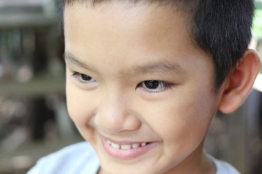 Bu yakın plan görüntü, açık havada saf neşe ve masumiyet gösteren parlak bir gülümseme ile mutlu bir çocuğu yakalar. Çocukluk hazzının mükemmel bir temsili..