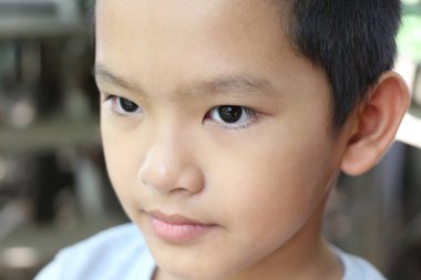 Yoğun bir ifade sergileyen düşünceli bir çocuğun yakın plan portresi. Çocuk düşünceli bir tavırla, masumiyeti ve merakı yakalıyor..