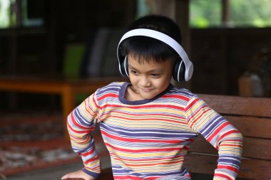 Neşeli bir çocuk evde otururken kulaklıkla müzik dinlemekten hoşlanır. Canlı kıyafet ve neşeli ifade kaygısız gençliğin özünü yakalar..
