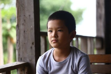 Genç bir çocuk düşünceli bir şekilde oturur, mesafeye bakar, bir anlık iç gözlem anı yakalar. Doğal ışık onun sakin yüz ifadesini güçlendirir, davetkar yansımasını..