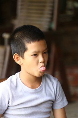 Neşeli bir çocuk dilini dışarı çıkararak komik bir yüz ifadesi takınır. Bu samimi portre çocukluk sevincinin ve kaygısız mizahın özünü yansıtıyor..