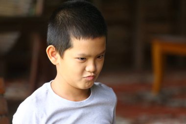 Ciddi ve düşünceli bir ifadeye sahip genç bir çocuk açık havada, çocukluğun masumiyetini ve çekiciliğini gösteren samimi bir anı yakalıyor..