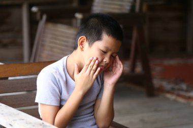 Düşüncelere dalmış, sessizce oturan genç bir çocuk. İfadesi bir dizi duyguyu yansıtıyor, bir anlık içgözlem ve tefekkür..