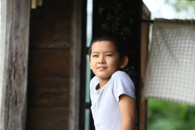Kendine güvenen genç bir çocuk açık havada rahat bir poz veriyor, neşe ve masumiyet sergiliyor. Doğal ortam çocukluk ve kaygısız ruhun tazeliğini vurgular..