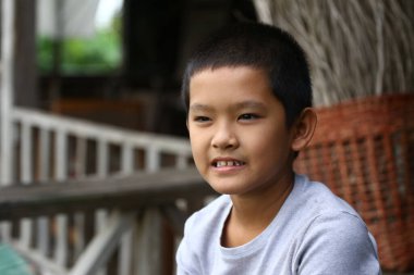 Neşeli bir çocuk dışarıda oturuyor, gerçek bir gülümseme sergiliyor. Doğal bir ortamda yakalanan bu portre, gençliği, mutluluğu ve masumiyeti yansıtıyor..