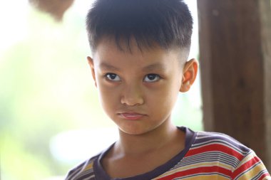 Genç bir çocuk yoğun bir bakış sergiliyor, doğal bir ortamda merak ve düşünceli bir anı yakalıyor, masumiyet ve duyguyu yansıtıyor..