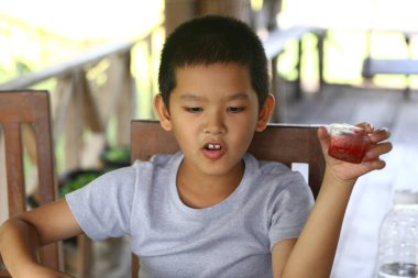 Genç bir çocuk kırsal bir ortamda dışarıda otururken bir çerez kavanozu tutuyor. Neşeli ifadesi çocukluk sevincini ve basit zevkleri yansıtıyor..