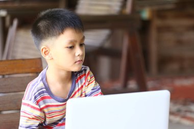 Odaklanmış bir çocuk evde dizüstü bilgisayarla meşgul oluyor, çocukluk ve teknoloji kavşağını vurguluyor. Sahne bir konsantrasyon ve öğrenme anını yakalar..