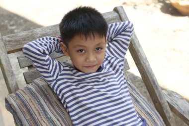 Genç bir çocuk güneşli bir günde rahat bir poz verir, sakin bir açık hava ortamında sıcaklığın ve rahatlığın tadını çıkarır..