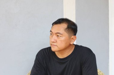 Siyah tişörtlü düşünceli bir adam dışarıda oturur, düşüncelere dalmıştır. Onun ciddi ifadesi ve rahat duruşu bir sakinlik ve içgözlem duygusu iletir..