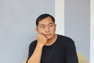 Düşünceli bir adam gündelik giysiler içinde düşünceli bir ifadeyle oturur ve hayatı yansıtır. Onun ciddi bakışları bir içgözlem ve yalnızlık havası yaratıyor..