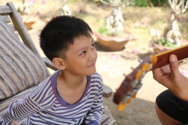Neşeli bir çocuk açık havada gitarla çalınan müziği dikkatle dinler, çocukluğun özünü ve doğanın güzelliğini sakin bir ortamda yakalar..