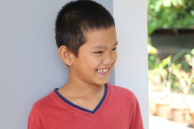 Neşeli genç bir çocuk parlak bir şekilde gülümsüyor, saf neşe sergiliyor. Doğal ışıkta yakalanan bu portre, basit bir arka plana karşı masumiyet ve neşe vurguluyor..