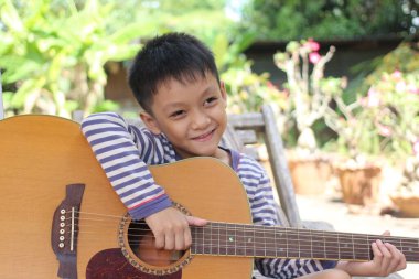 Neşeli genç bir çocuk bahçede oturur, gitar çalar. Neşeli gülüşü ve neşeli duruşu çocukluk yaratıcılığının ve eğlencenin özünü yansıtıyor..