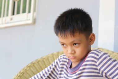 Düşünceli bir çocuk ciddi bir ifadeyle içeride oturur, derin duygular ve tefekkür gösterir. Onun yoğun bakışları bir anlık yansımayı ya da hayal kırıklığını akla getiriyor..