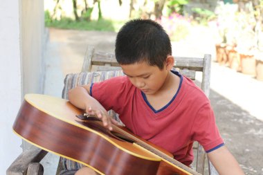 Genç bir çocuk dışarıda oturur, gitar çalmaya konsantre olur. Güneş ışığı, müzik yeteneğini barışçıl bir ortamda keşfederken sıcak bir atmosfer yaratıyor..