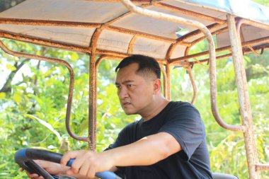 Odaklanmış bir traktör operatörü yemyeşil alanda gezinerek tarım alanında sıkı çalışmayı gösteriyor. Canlı manzara kırsal yaşamı ve çalışkan ruhu vurguluyor..