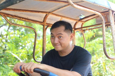 Neşeli bir adam açık havada küçük bir araç sürmekten hoşlanır. Neşeli ifadesi, doğadaki macera ve eğlencenin özünü yakalıyor..