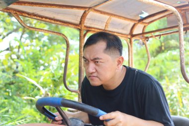 Azimli bir adam, verimli yeşil bir arazide yoğun bir şekilde vintage bir traktör kullanıyor. Tarımsal bir ortamda odak ve adanmışlık sergiliyor..