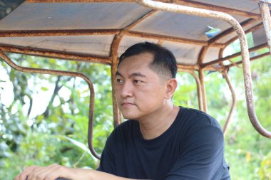 Düşünceli bir adam yemyeşil bir ortamda sakin bir anın tadını çıkararak düşünceli bir ifade sergiliyor. Bu portre doğadaki sükunetin özünü yansıtıyor..