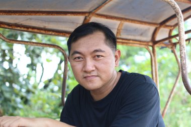 Düşünceli bir adam açık havada rahat ve rahat bir ortamda poz veriyor, canlı yeşillikler arasında sakin ifadeler sergiliyor. Yaşam tarzı temaları için ideal.