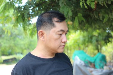 Düşünceli bir adam yemyeşil bir alanda duruyor, dalgın dalgın dalgın dalgın dalgın. Dışarıdaki dingin ortam bir huzur ve iç gözlem anı yakalıyor. Rahatlama ve tefekkür temaları için mükemmel..