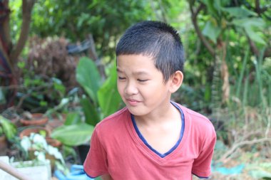 Açık havada, yemyeşil bir bahçede eğlenen neşeli bir çocuk. Neşeli ifadesi çocukluk masumiyetinin ve doğadaki keşiflerin özünü yakalıyor..