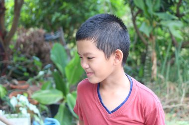 Neşeli genç bir çocuk açık havada eğleniyor, canlı bir doğal ortamda gülümsüyor. Neşeli ifadesi çocukluk sevincinin ve masumiyetin özünü yakalıyor..