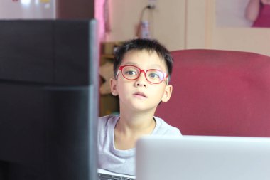 Odaklanmış genç bir çocuk evdeki bir bilgisayar üzerinde özenle çalışıyor, öğrenme sürecindeki konsantrasyonunu ve bağlılığını gösteriyor. Eğitim temaları için ideal.