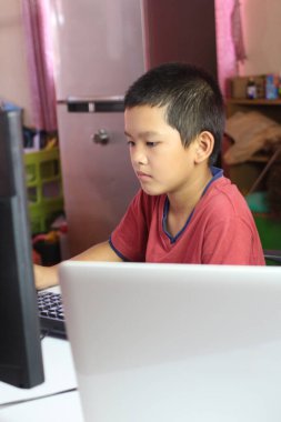 Genç bir çocuk rahat bir iç mekanda bilgisayarına yoğunlaşıyor, modern teknolojinin eğitim ve kişisel gelişimdeki rolünü vurguluyor..