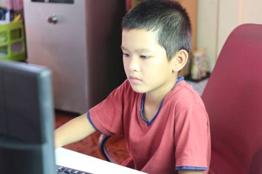 Genç bir çocuk bilgisayar ekranına odaklanmış çalışırken konsantrasyonunu ve kararlılığını gösteriyor. Sahne öğrenmenin ve dijital ilişkinin özünü yakalıyor..