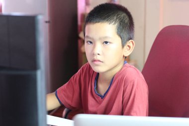 Genç bir çocuk evdeki bilgisayarına odaklanmış öğrenme ve teknolojiye olan bağlılığını sergiliyor. Eğitim ve yaşam tarzı temaları için mükemmel.