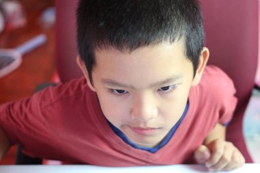 Yaratıcı faaliyetlerine, azim ve konsantrasyonuna derinden odaklanmış genç bir çocuk. Onun ciddi ifadesi öğrenme ve bağlanma anını yakalıyor..