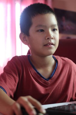 Genç bir çocuk evde oturur, bilgisayar ekranına odaklanır, keşif ruhunu somutlaştırır ve dijital deneyimlerle öğrenir..