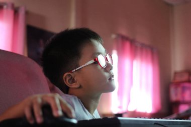 Gözlük takan odaklanmış bir çocuk pembe perdeli loş bir odada bilgisayarın başında oturuyor. Sahne, gençliğin özünü ve konsantrasyonunu rahat bir ortamda yakalıyor..